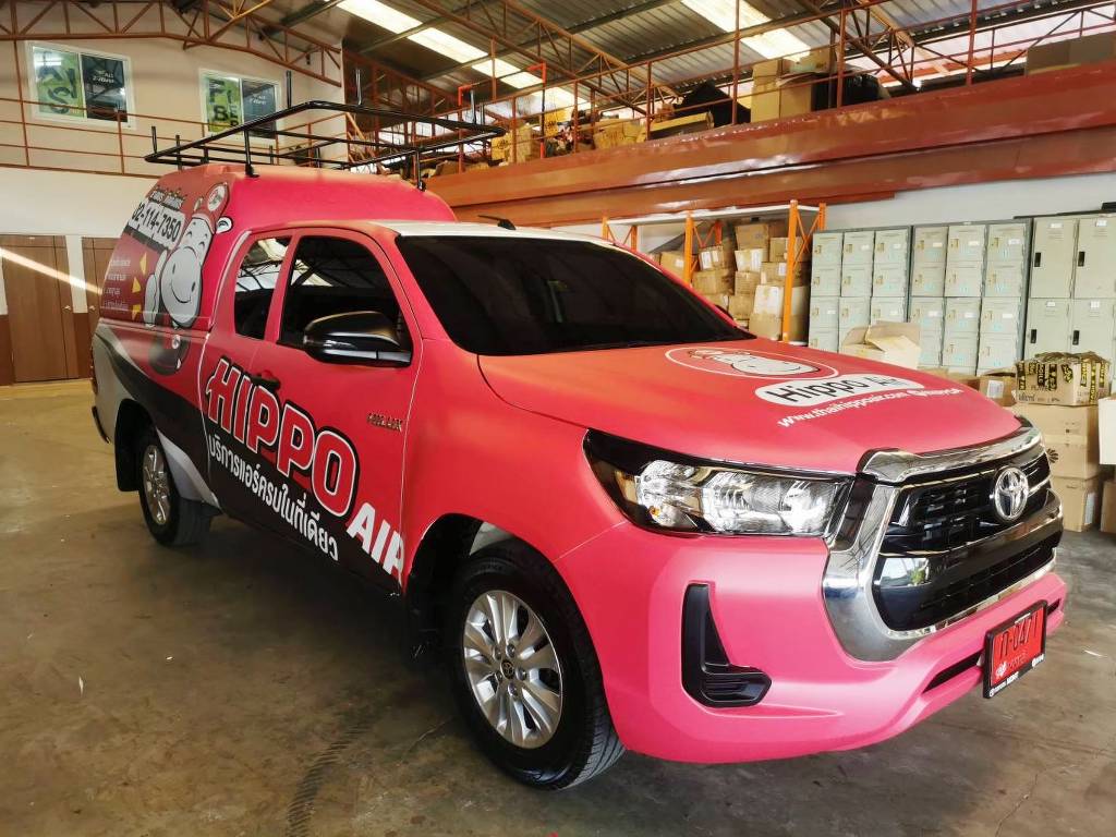 สติ๊กเกอร์แร๊ปรถบริการภาคสนาม มุมเฉียงหน้ารถกระบะ Toyota Hilux Revo แร็ปปิดผิวฝากระโปรงหน้ารถยนต์ด้วยโทนสีชมพูมาเจนต้าสลับโลโก้ตราสินค้าวงกลม