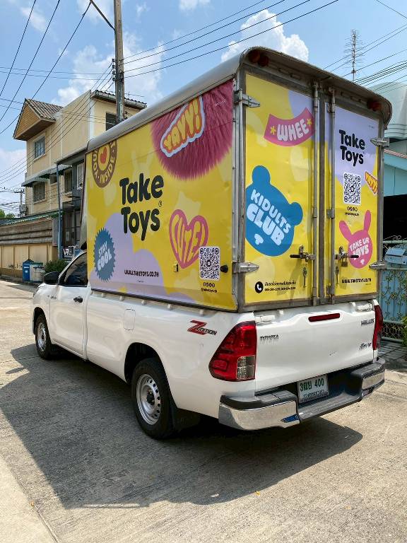 สติ๊กเกอร์รถส่งของ มิติมุมเฉียงท้ายรถบรรทุกส่งสินค้าแบรนด์ Take Toys โชว์ลวดลายดีไซน์พิกเซลพาสเทลคาดระนาบตัวอักษร Kidults Club เพิ่มความโดดเด่น