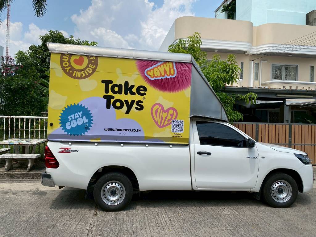 สติ๊กเกอร์รถส่งของ ภาพถ่ายระนาบด้านข้างขวาเต็มคันรถกระบะตอนเดียว Toyota Hilux Revo แร๊ปตู้ทึบสีกราฟิกเหลืองสดใสสลับม่วงแบรนด์ Take Toys คมชัดสูง