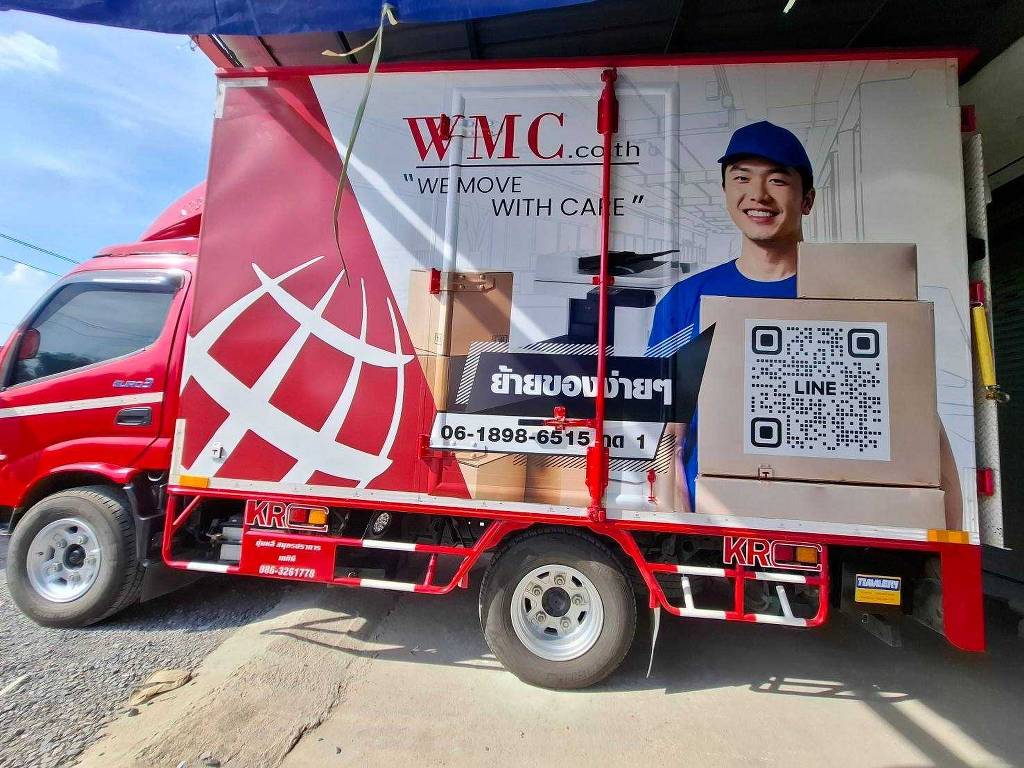 สติ๊กเกอร์แร๊ปรถขนส่งโลจิสติกส์ ด้านข้างเต็มแผงตู้รถบรรทุก 4 ล้อใหญ่ WMC แสดงภาพพรีเซนเตอร์พนักงานชายสวมหมวกแก๊ปถือกล่องพัสดุและ QR Code ขนาดใหญ่ชัดเจน