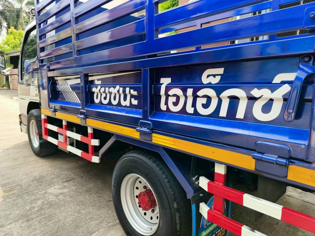 สติ๊กเกอร์โลโก้และชื่อบริษัทสีขาวตัดกับพื้นรถบรรทุกสีน้ำเงิน สร้างความเป็นมืออาชีพ