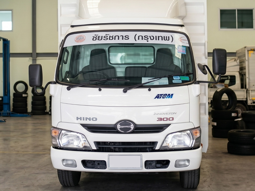 สติ๊กเกอร์คาดแถบรถองค์กรข้อความ ชัยรัชการ (กรุงเทพ) บนกระจกหน้ารถบรรทุก เปรียบเทียบกับงานกราฟิกขนาดใหญ่เพื่อเน้นความเรียบสุภาพ