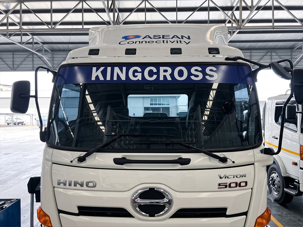 สติ๊กเกอร์คาดแถบรถองค์กรสีน้ำเงินอักษรขาว KINGCROSS บนกระจกหน้ารถบรรทุก Hino Victor 500 เพื่อเปรียบเทียบกับงานแร็ปเต็มคัน