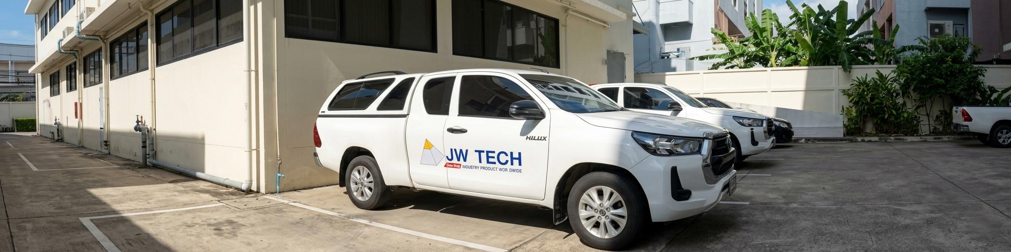 แถวรถกระบะทีมขายสีขาวติดสติ๊กเกอร์โลโก้ JW TECH บนตัวถังและตู้หลังคาอย่างสม่ำเสมอและถูกต้องตามมาตรฐานแบรนด์
