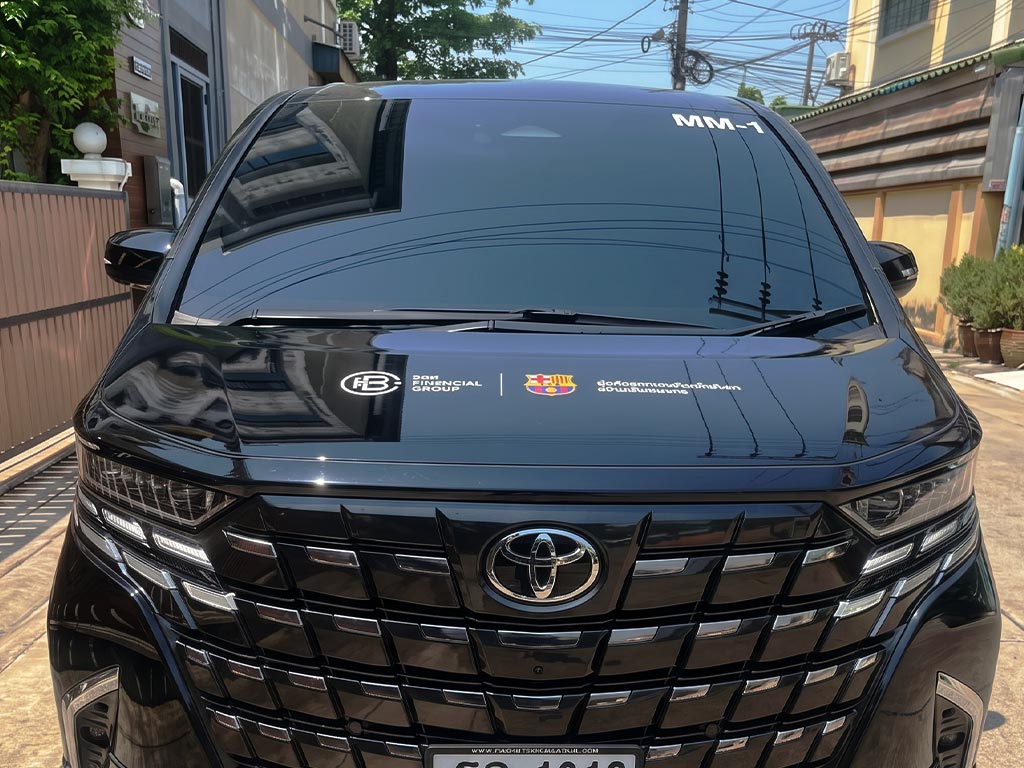 สติ๊กเกอร์เลขรถบริษัทรหัส MM-1 บนกระจกหน้ารถตู้ผู้บริหาร Toyota Alphard สีดำ พร้อมโลโก้องค์กรบนฝากระโปรงรถ