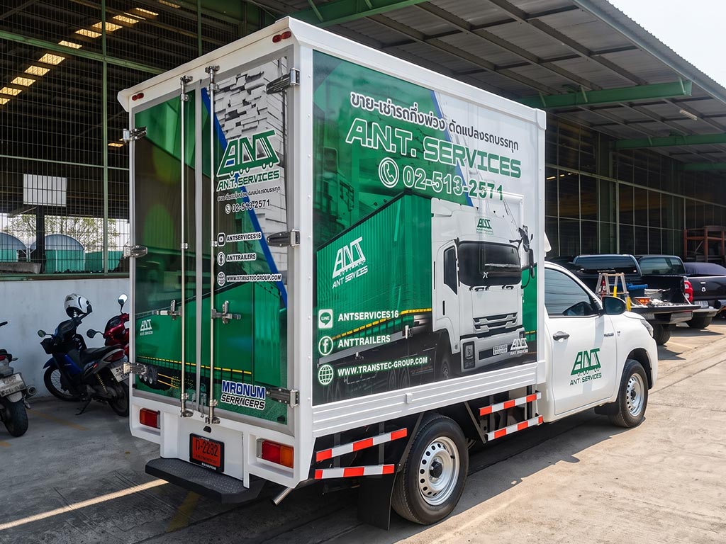 สติ๊กเกอร์ประชาสัมพันธ์เคลื่อนที่ ลายโฆษณา A.N.T. SERVICES สีเขียวขาวด้านหลังตัวถังตู้ทึบรถกระบะขนส่งอุตสาหกรรมในมุมมองเฉียงตอนท้าย