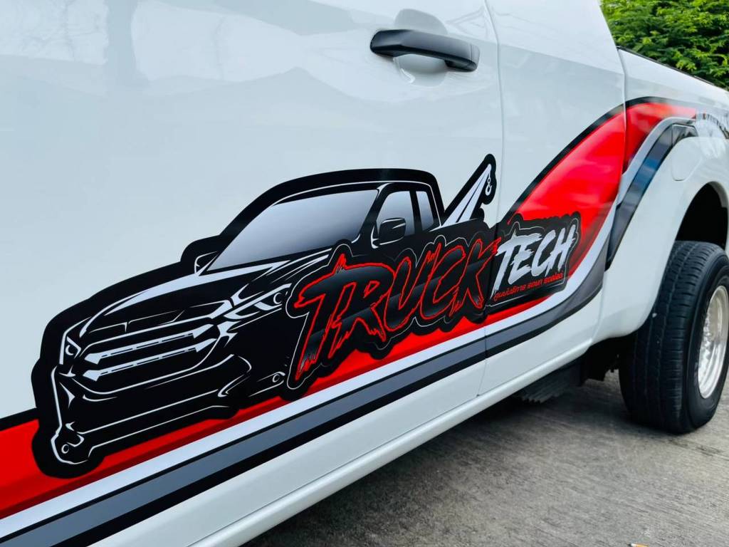 รายละเอียดระยะใกล้ชิ้นงานสติ๊กเกอร์โลโก้ Truck Tech และลายกราฟิกสีแดงดำบนประตูรถกระบะบริษัท