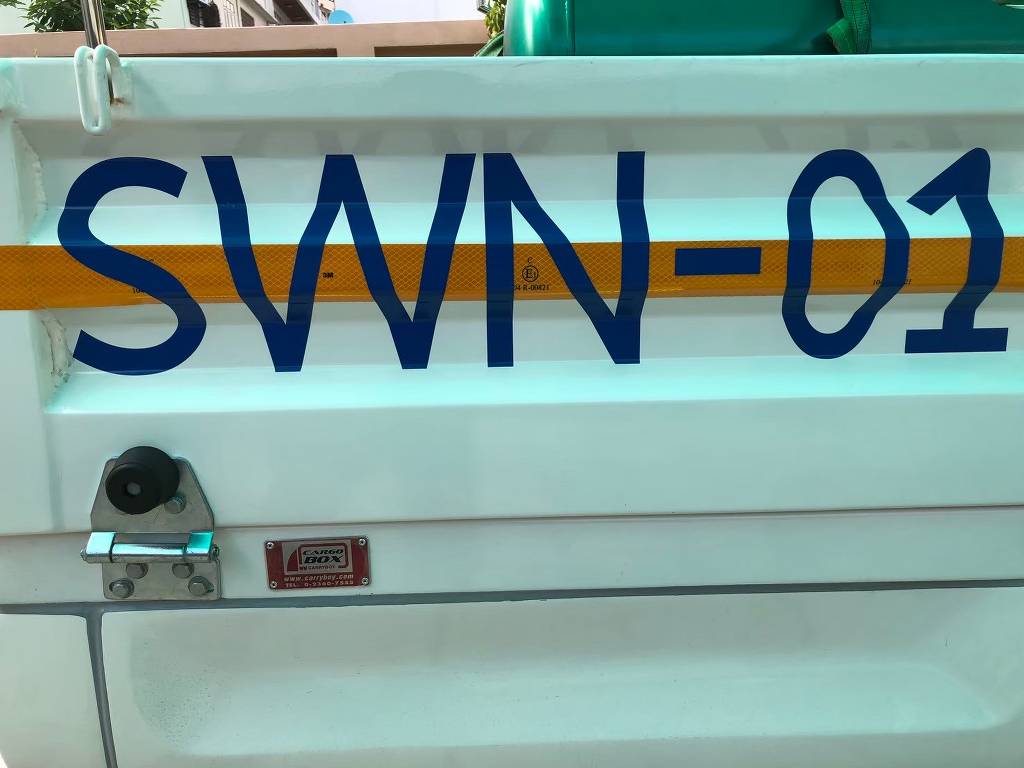 สติ๊กเกอร์เลขรถบริษัทรหัส SWN-01 ร่วมกับแถบสะท้อนแสงนิรภัยสีเหลืองบริเวณข้างตัวถังรถกระบะขนส่งสินค้า