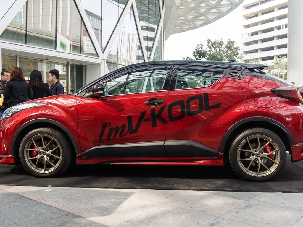 รถครอสโอเวอร์สีแดงใช้งานองค์กร ติดสติ๊กเกอร์ตัวอักษรไดคัทชื่อแบรนด์ V-KOOL สีดำเงาบริเวณประตูข้างเพื่อความเรียบหรูและเป็นมืออาชีพ