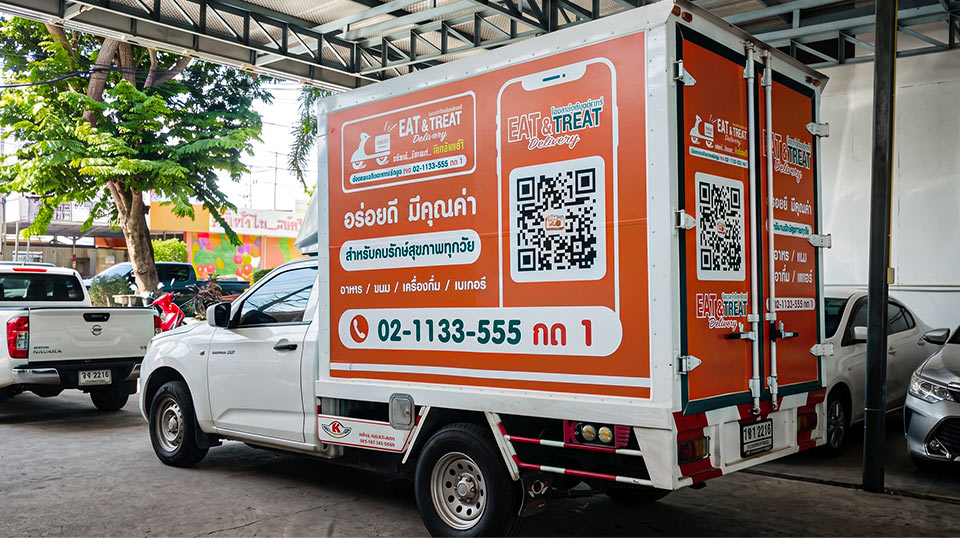 สติ๊กเกอร์เปลี่ยนข้อมูลติดต่อบนตู้รถบรรทุกสีส้ม จัดวางคิวอาร์โค้ดขนาดใหญ่ด้านข้างและเบอร์โทรศัพท์ด้านท้าย