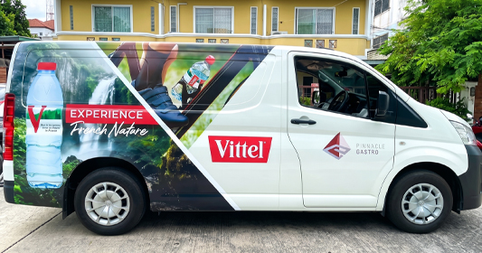 รถตู้ Toyota ติดสติ๊กเกอร์โฆษณาน้ำแร่ Vittel และแบรนด์ Pinnacle Gastro ข้างตัวถัง