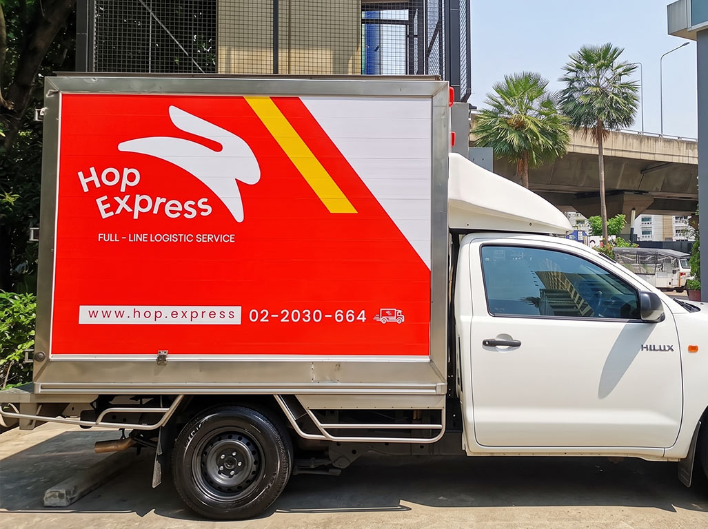 สติ๊กเกอร์เว็บไซต์บนรถ ขนส่งตู้ทึบ Hop Express แสดงการตีกรอบเน้นข้อความ URL คู่กับเบอร์ติดต่อเพื่อการจดจำ
