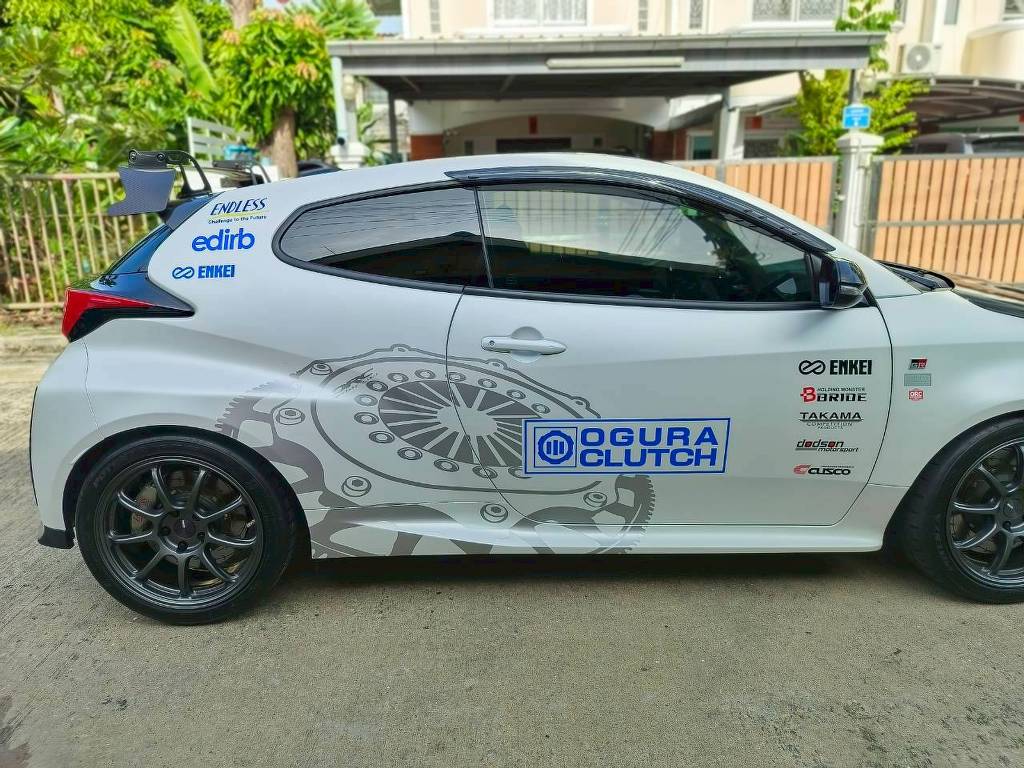 สติ๊กเกอร์ประชาสัมพันธ์เคลื่อนที่ มุมมองระนาบด้านขวาเต็มคันรถยนต์ GR Yaris สีขาว ลายโฆษณาคลัตช์และแผงโลโก้สปอนเซอร์แนวดิ่ง