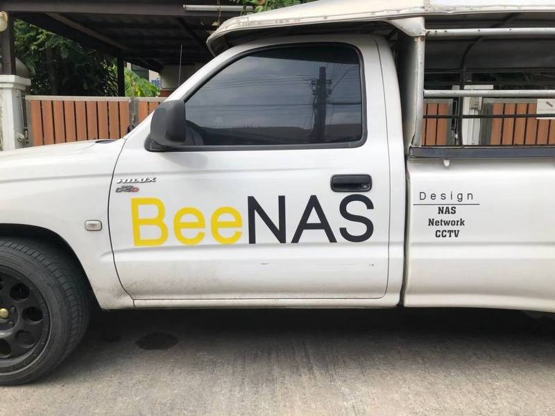 แผงประตูข้างฝั่งซ้ายของรถกระบะตอนเดียวสีขาว ติดตั้งสติ๊กเกอร์ชื่อบริษัทบนรถแบรนด์ BeeNAS เพื่อควบคุมความสมมาตรเท่ากันรอบคัน