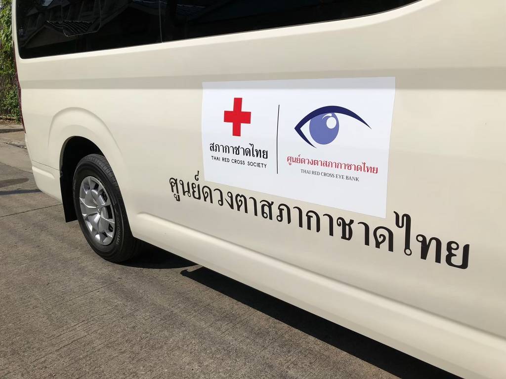 การจัดวางระบบสัญลักษณ์และสติ๊กเกอร์โลโก้บริษัทบนรถยนต์ประเภทรถตู้หน่วยงานสภากาชาดไทยเพื่อความเป็นทางการระดับสถาบันและความชัดเจนแม่นยำของอัตลักษณ์องค์กร