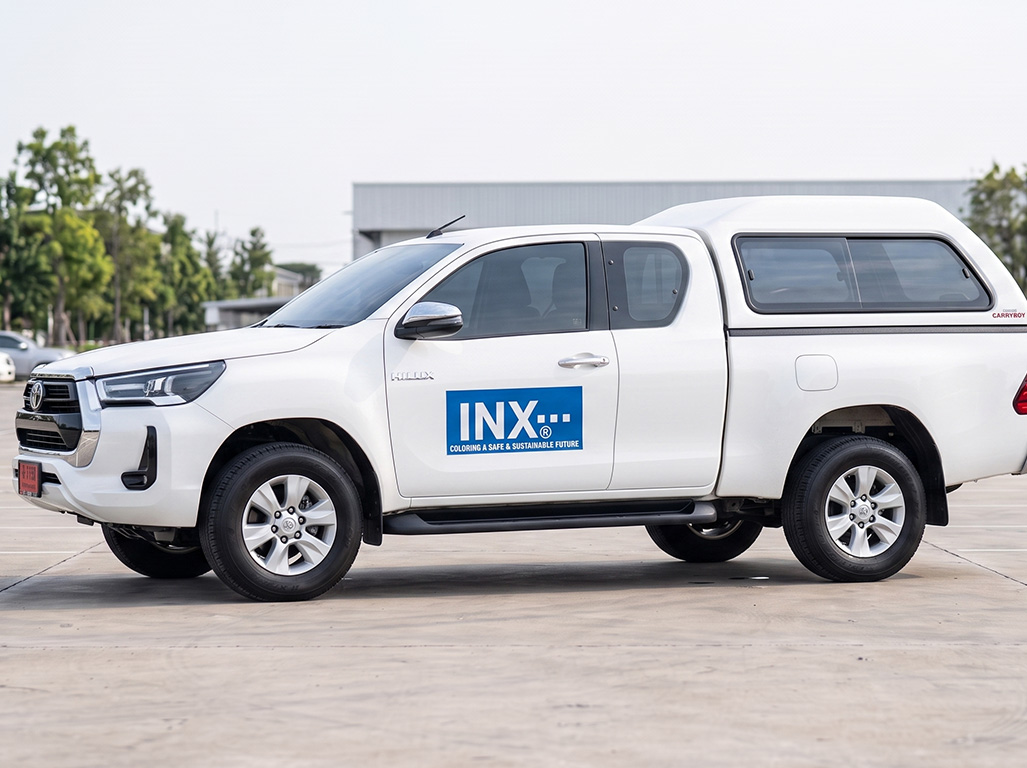 สติ๊กเกอร์ชื่อบริษัทบนรถกระบะ Toyota Hilux Revo มุมมองเฉียงด้านหน้าขวา ติดตั้งสติ๊กเกอร์แบรนด์สี่เหลี่ยมสีน้ำเงินที่ประตูฝั่งคนขับ