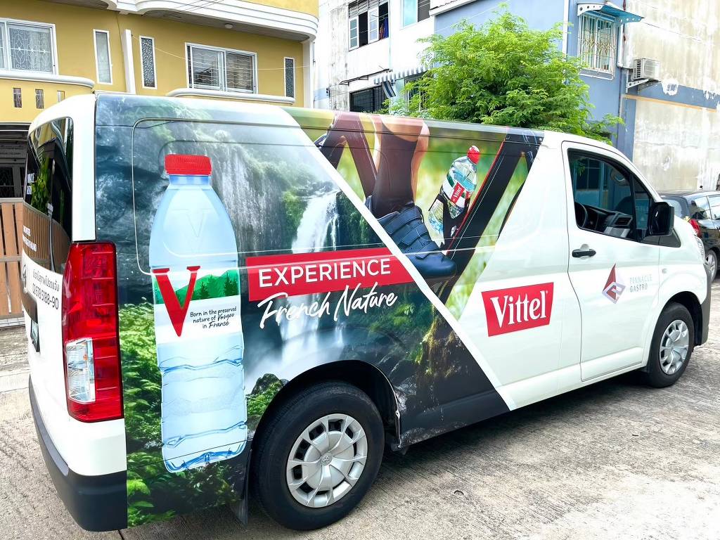 สติ๊กเกอร์ประชาสัมพันธ์เคลื่อนที่ ลาย Vittel EXPERIENCE French Nature มุมมองเฉียงจากด้านหลังรถตู้สีขาว โชว์งานต่อลายกราฟิกต่อเนื่อง