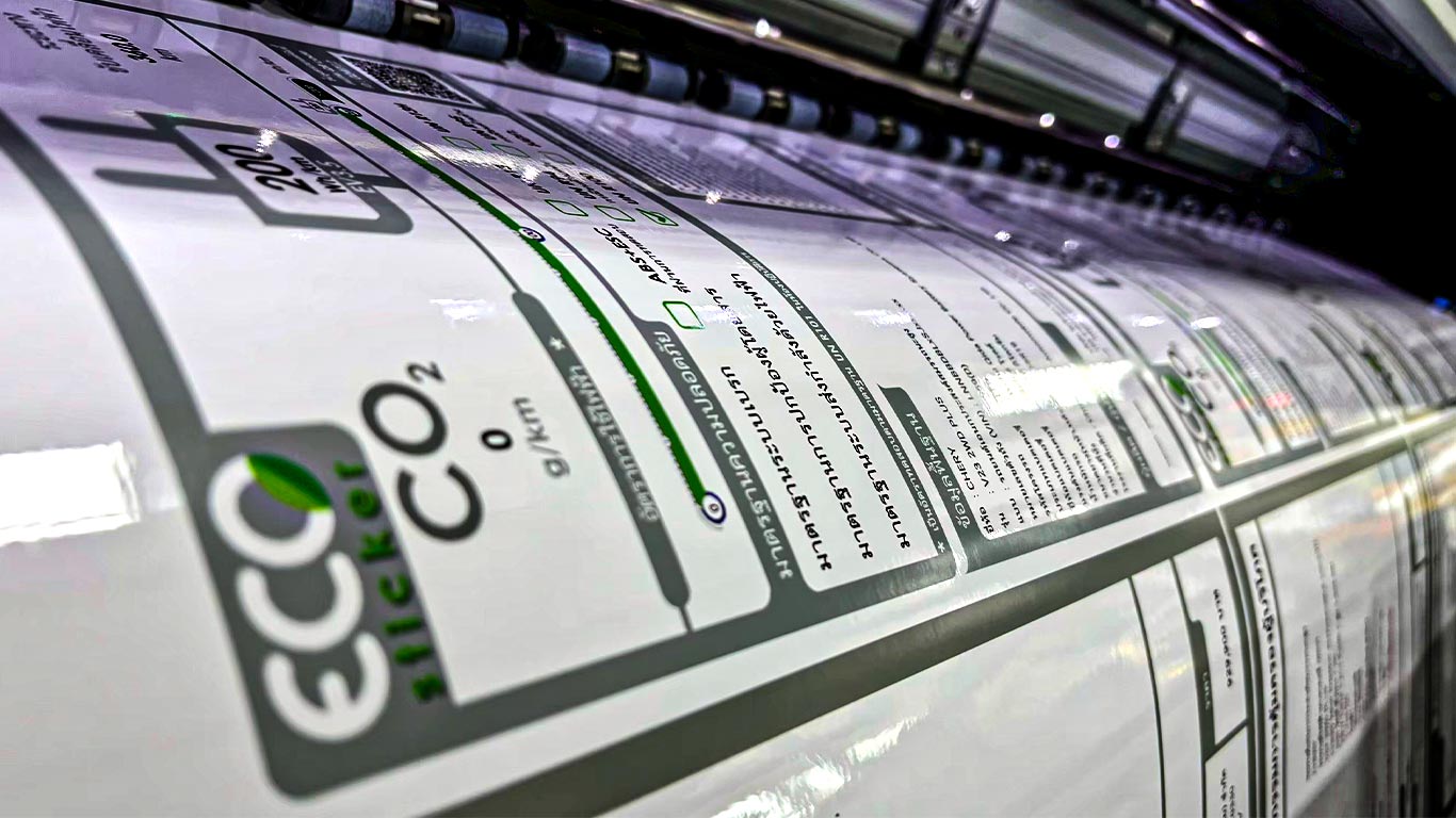 เครื่องพิมพ์ม้วนกำลังพิมพ์ฉลาก ECO Sticker แสดงข้อมูล CO2 และมาตรฐานความปลอดภัย