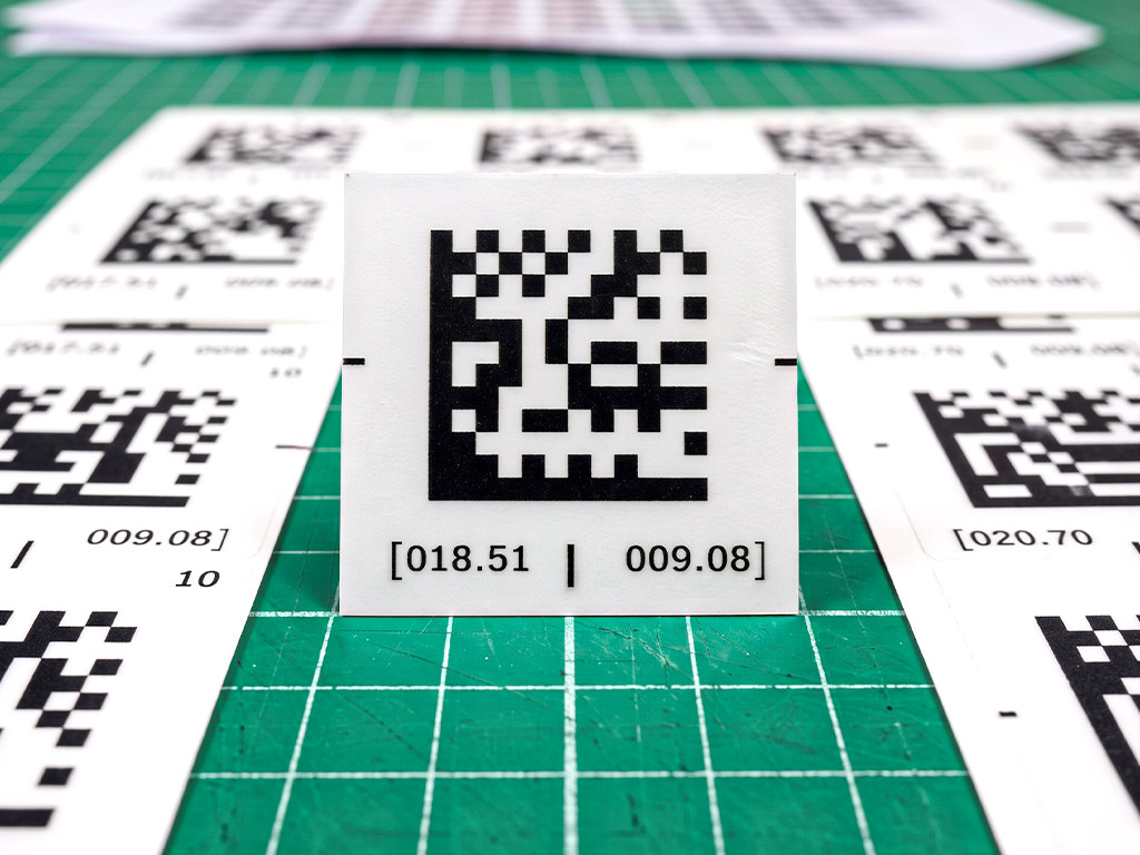 สติ๊กเกอร์บาร์โค้ดโรงงาน แบบ 2D Data Matrix แสดงพิกัด 018.51 และ 009.08 คมชัดระดับไมโคร