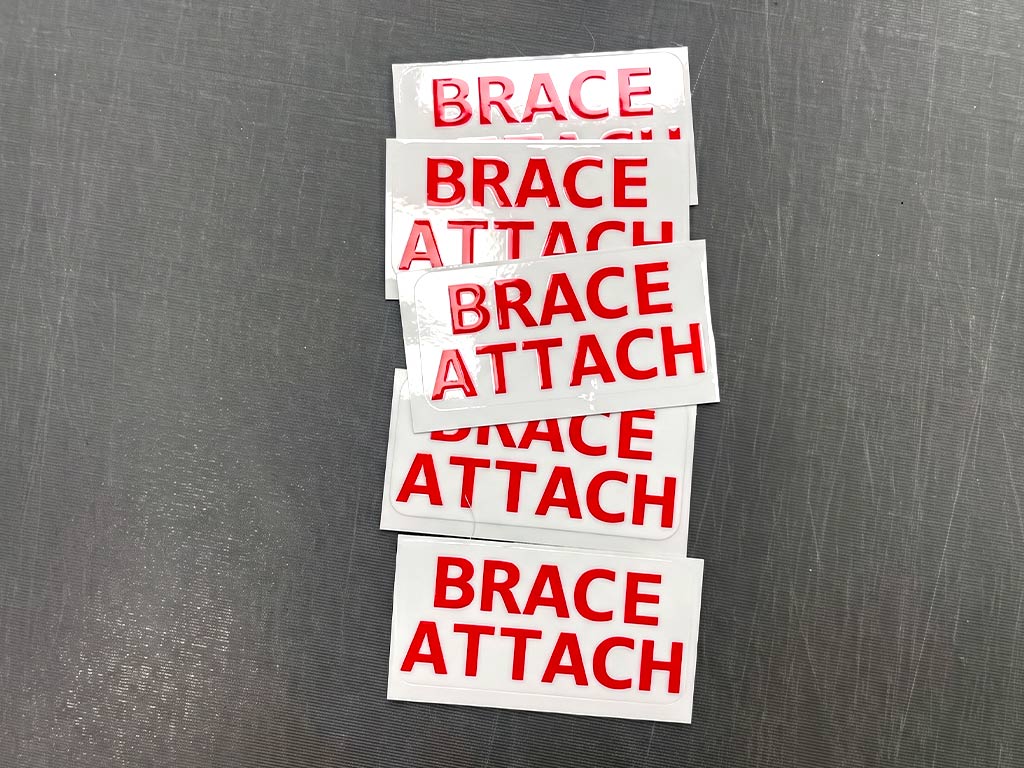 ป้ายความปลอดภัยโรงงาน สติ๊กเกอร์ระบุตำแหน่ง BRACE ATTACH ตัวอักษรสีแดง จัดซ้อนเป็นชุดพร้อมใช้งาน
