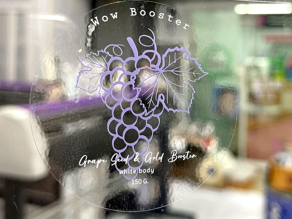 ฉลากใสพิมพ์สีขาว White Ink โลโก้พวงองุ่นสีม่วงและตัวหนังสือสีขาว Wow Booster ดีไซน์วงกลม