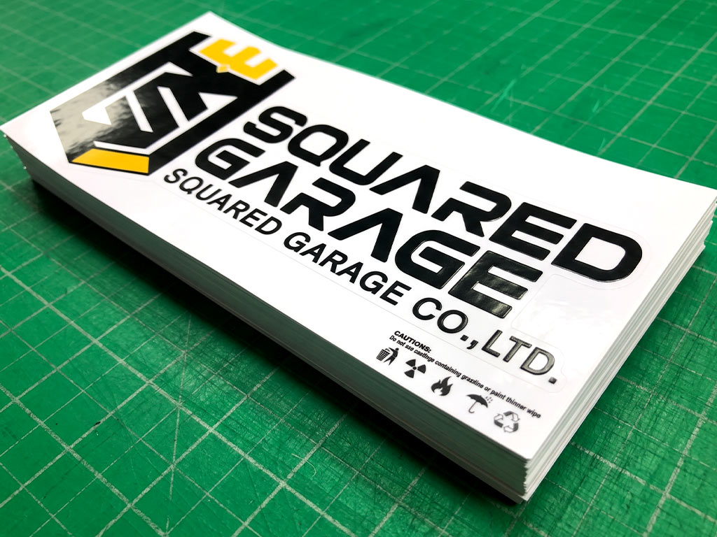 สติ๊กเกอร์ทนความร้อนเคลือบเงา SQUARED GARAGE มุมมองเฉียง แสดงมิติขอบไดคัทและปึกสติ๊กเกอร์