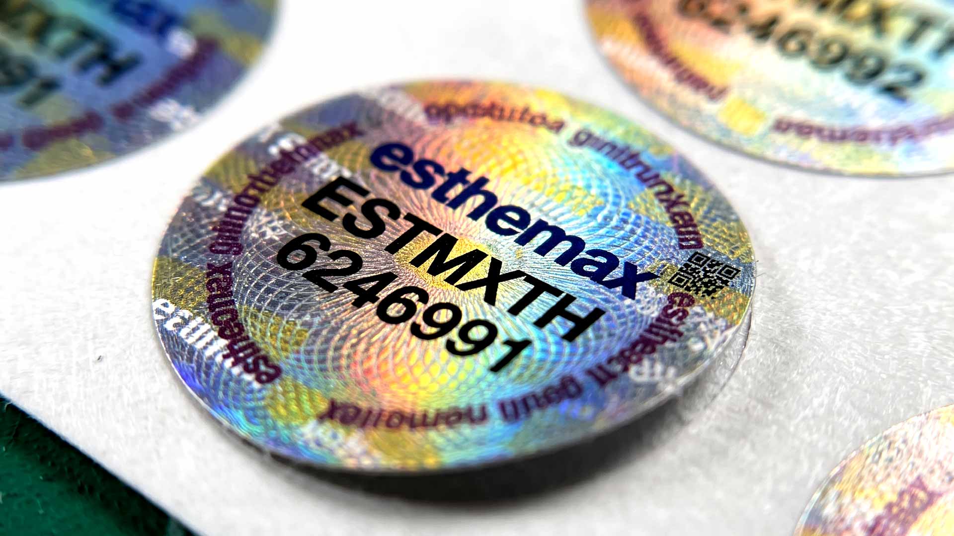 สติ๊กเกอร์ Security Seal โฮโลแกรมทรงกลมพิมพ์โลโก้ esthemax รหัสรุ่น ESTMXTH เลขรัน 6246991 และ QR Code สำหรับตรวจสอบย้อนกลับ