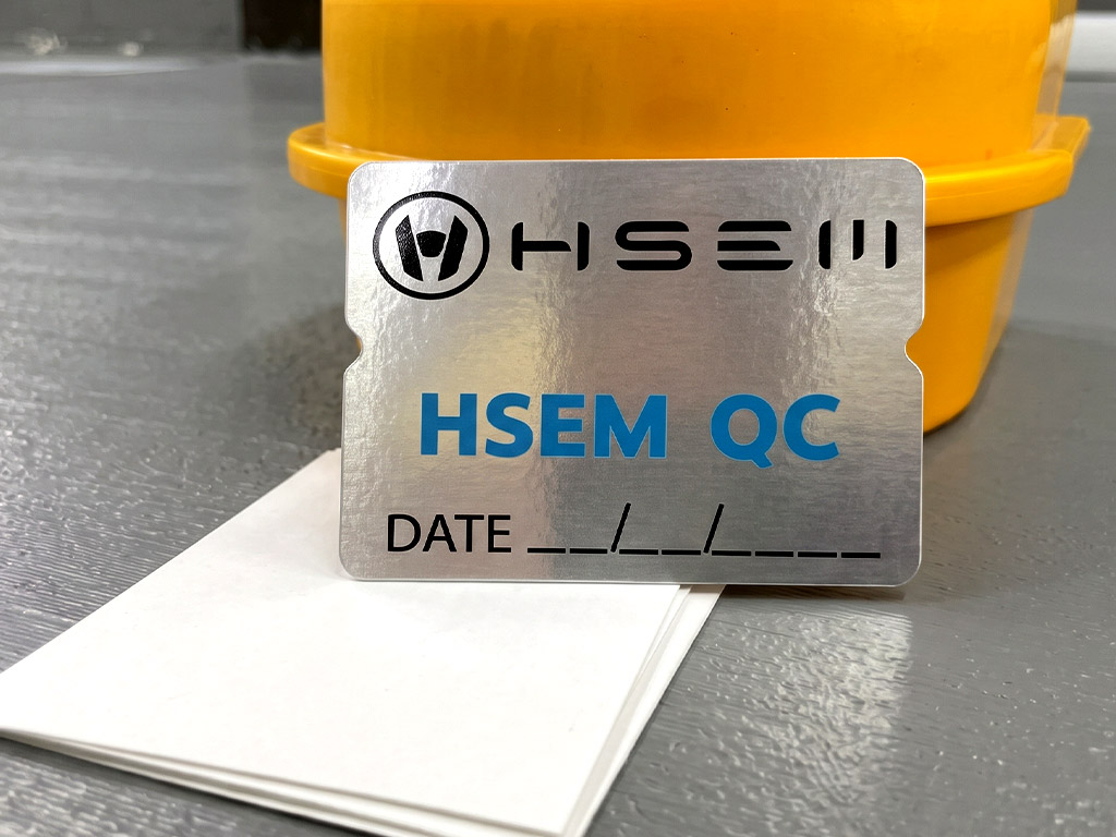 ฉลาก QC, Lot, Batch และ Traceability สติ๊กเกอร์ฟอยล์เงิน HSEM QC ภาพหน้าตรง แสดงสัดส่วนโลโก้และช่องกรอกวันที่