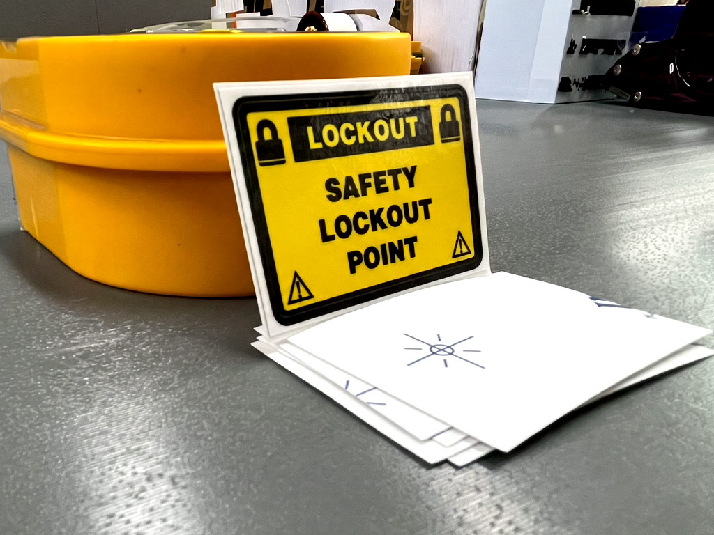 ป้ายความปลอดภัยโรงงาน สติ๊กเกอร์ SAFETY LOCKOUT POINT จัดซ้อนเป็นชุดบนแผ่นรองหลังสีขาว