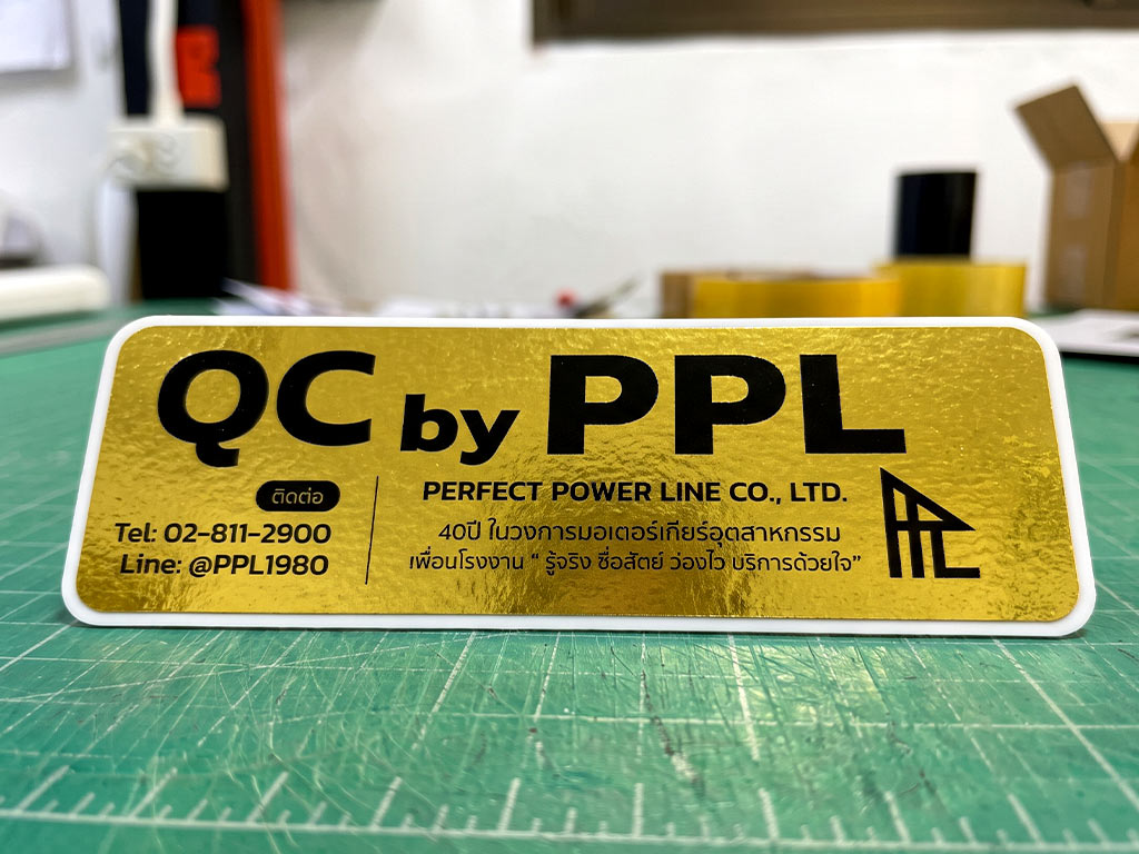 ฉลาก QC, Lot, Batch และ Traceability สติ๊กเกอร์ฟอยล์ทอง QC by PPL วางบนโต๊ะทำงานในแผนกประกอบ