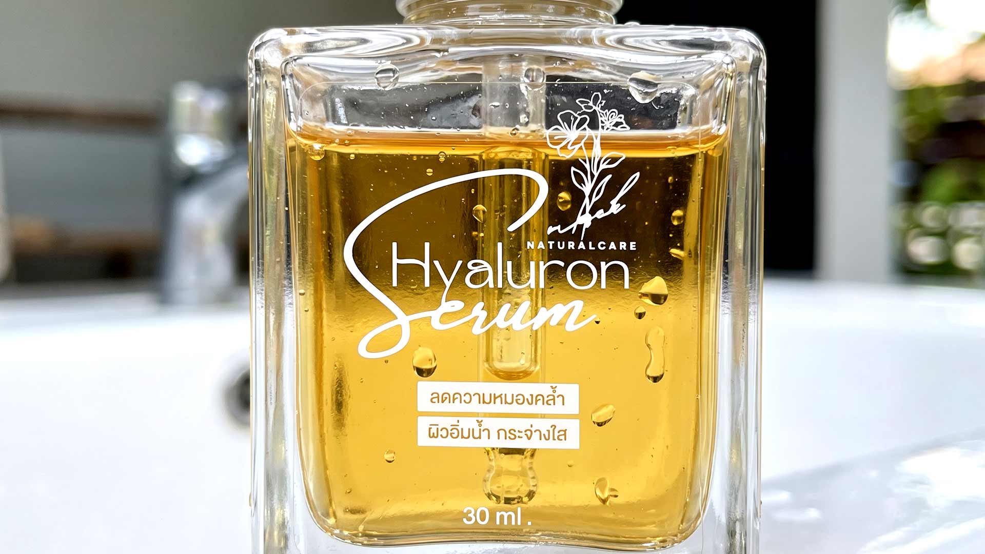 ฉลากใสพิมพ์หมึกขาว UV ติดขวดแก้วเซรั่ม Hyaluron แสดงเทคนิค Selective White Ink อักษรสีขาวคมชัดบนเนื้อเซรั่มสีทอง