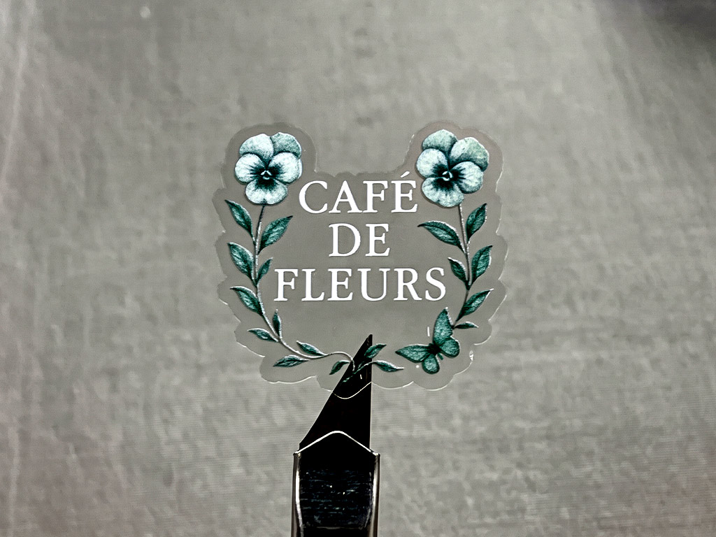 ฉลากใสพิมพ์สีขาว Transparent UV ข้อความ CAFÉ DE FLEURS ช่อดอกไม้สมมาตร คอนทราสต์ชัดเจน
